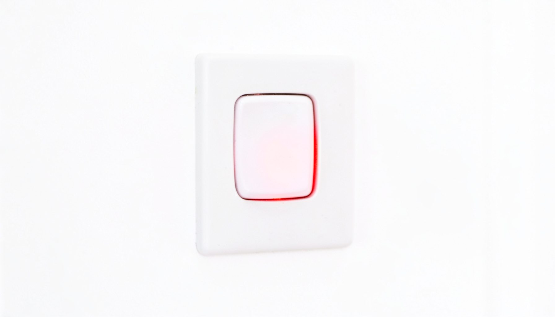 Close-up of a wall-mounted push-button security lock switch with a glowing red indicator light, set against a clean white background